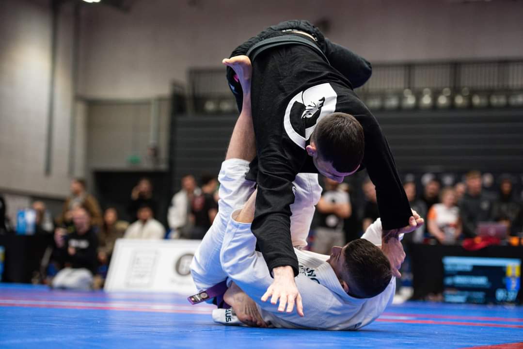 An Alliance jiu jitsu fighter performing a takedown in a competition